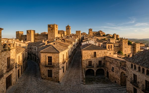 Golden evening light over the medieval stone towers, tiled rooftops and cobbled lanes of Cáceres old town in Extremadura